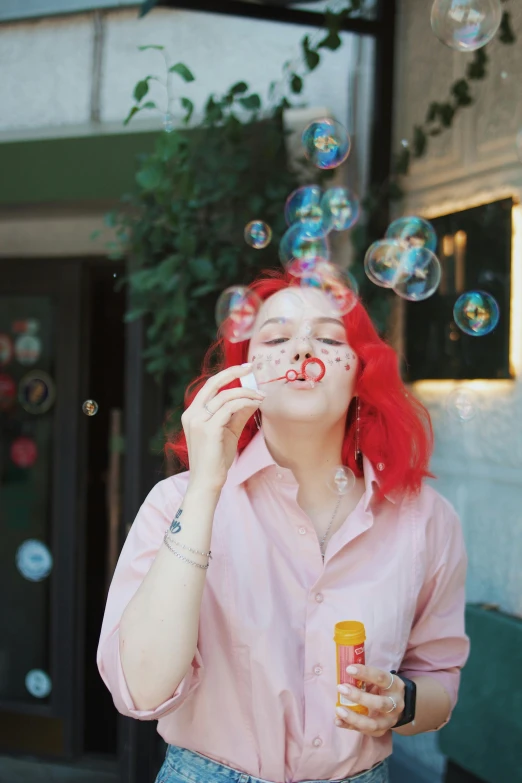 a woman with red hair blowing bubbles over her face