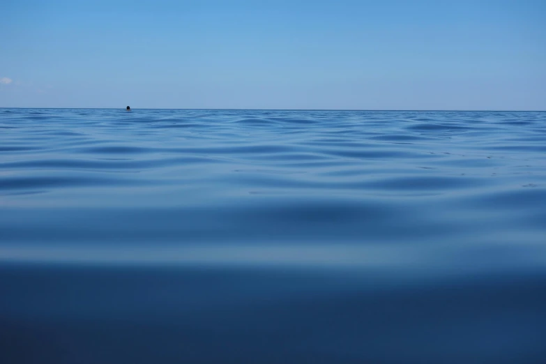 the ocean is blue and has a lone boat floating in the distance