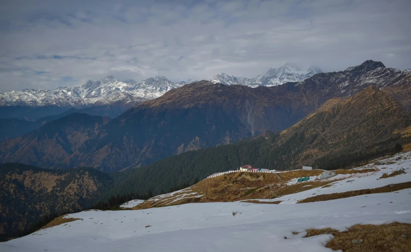 a snowy mountain with some trees and mountains in the background