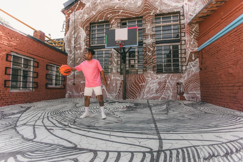 a man in a pink shirt holding a ball next to a building