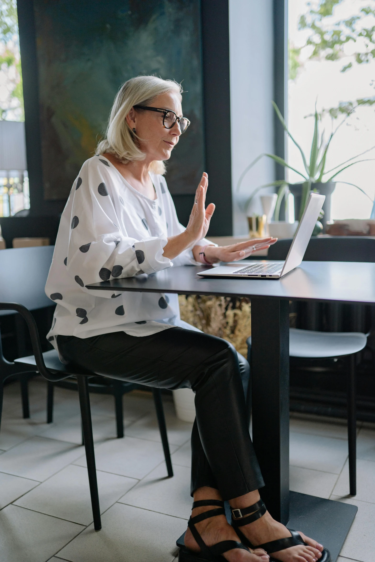 a woman sitting at a table using her laptop computer