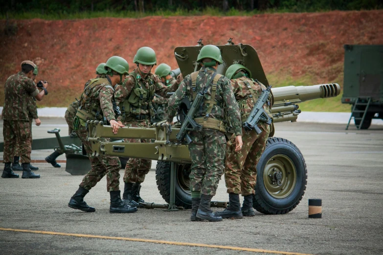 several military men, with camouflage uniforms and green hats, examine a large machine gun on the street