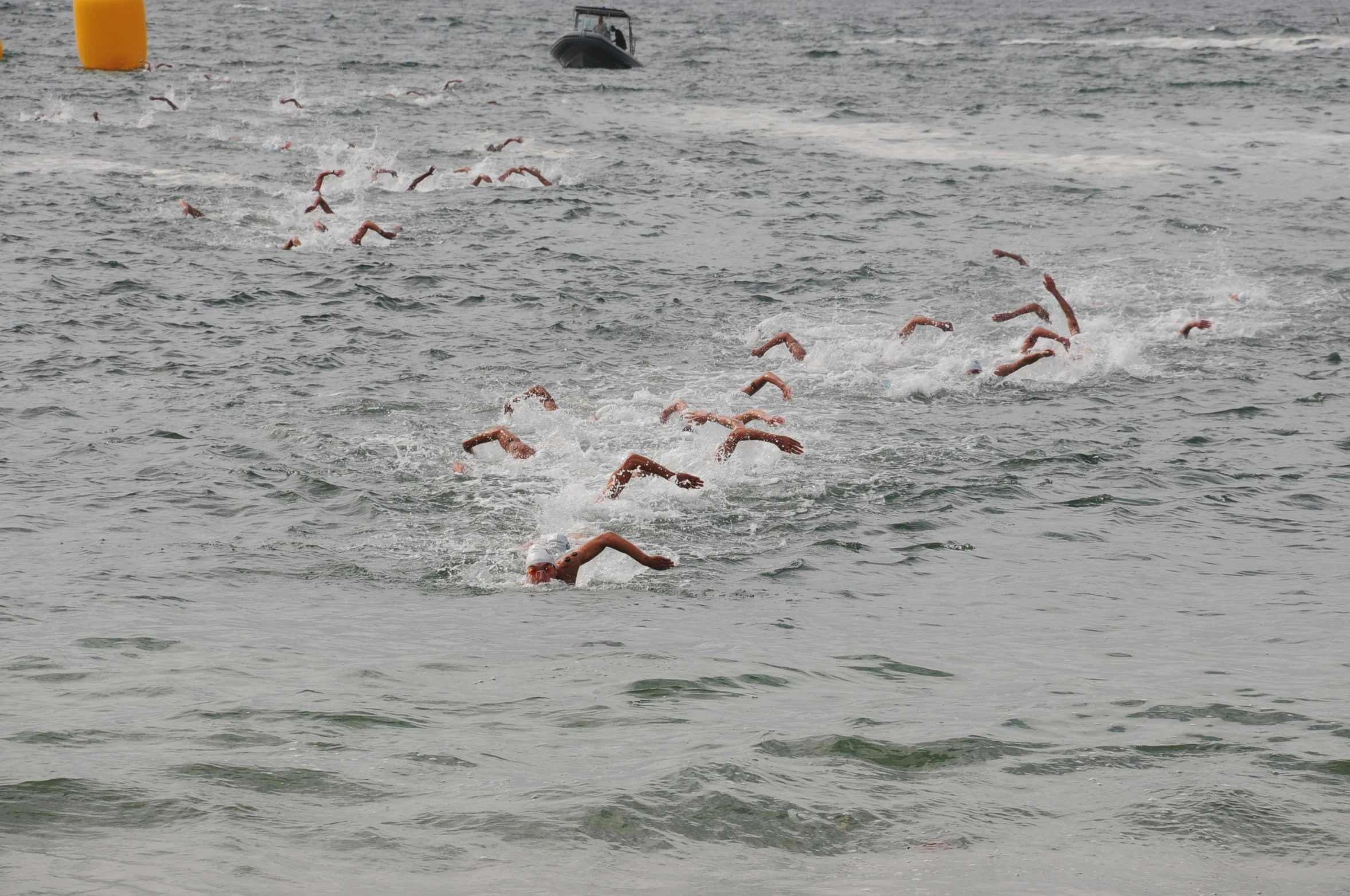 several swimmers racing off the back of a boat in the ocean