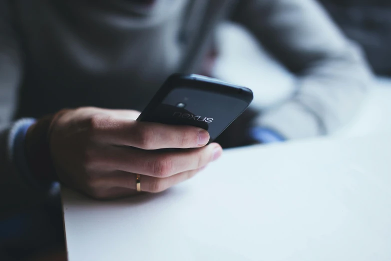 someone holding their phone in each hand while sitting at the table