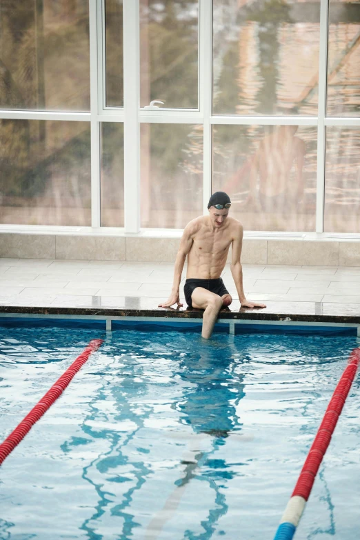 a shirtless man sitting on a swimming pool