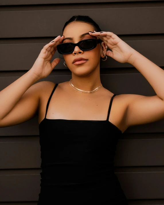 a beautiful young woman wearing sunglasses while standing by a wall