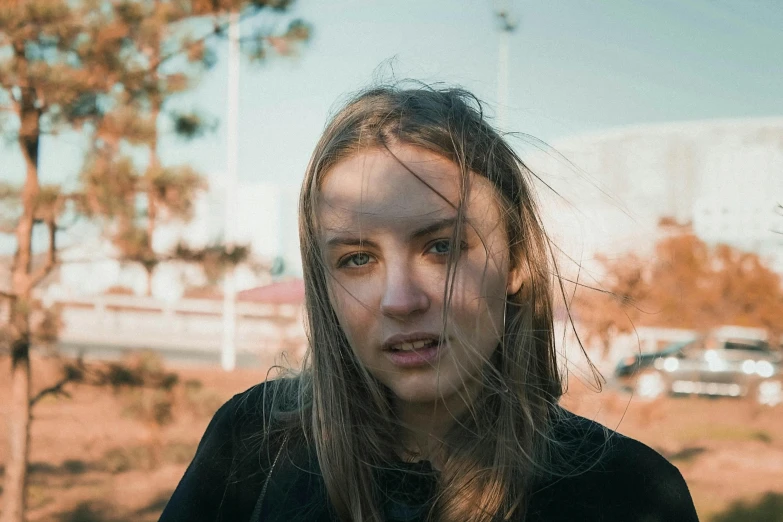 a girl with long hair standing in front of a parking lot