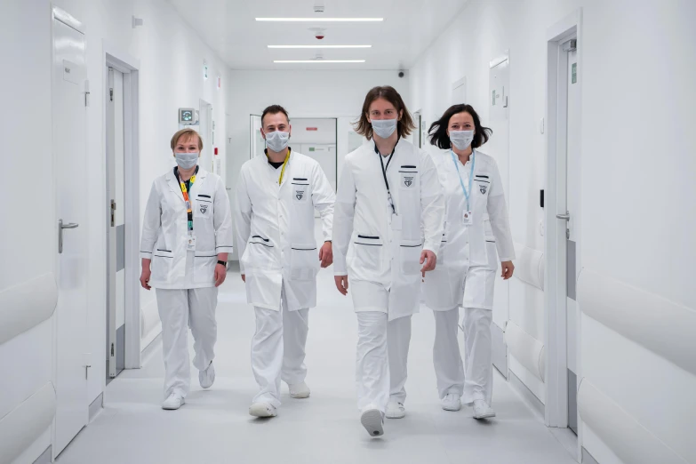 a group of people walking down a hallway wearing medical suits