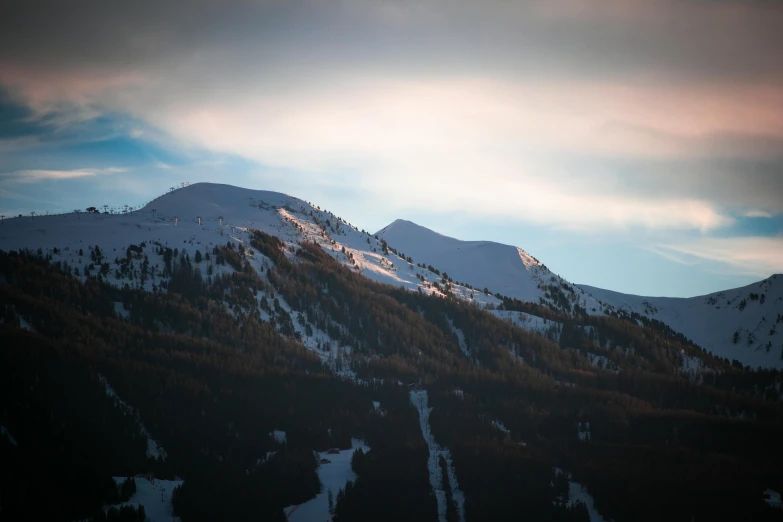 the mountains are covered in snow on a cloudy day