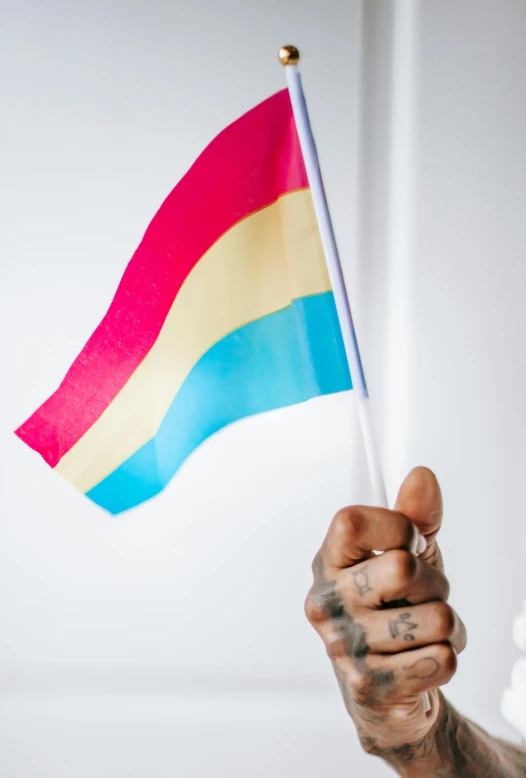 a man holds a rainbow colored flag in his hand