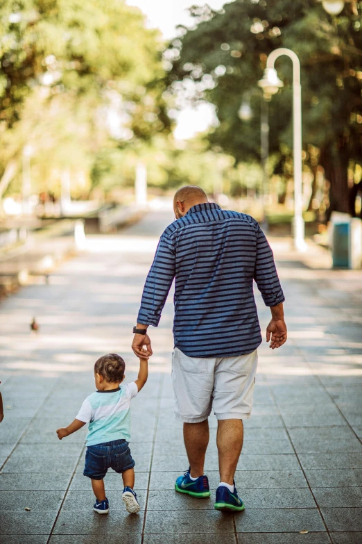 a man holds the hand of a  walking down a sidewalk