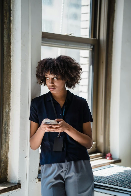 the young lady is wearing blue pants and has a phone in her hand