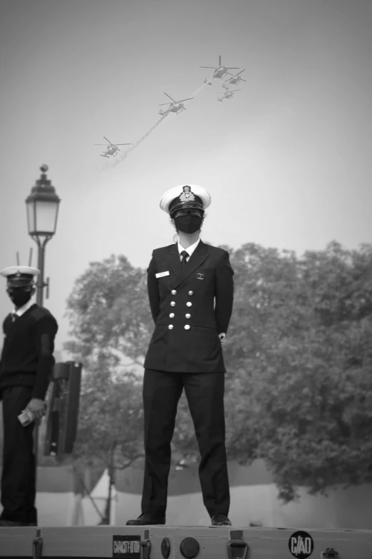 a man in a naval uniform standing on top of a vehicle