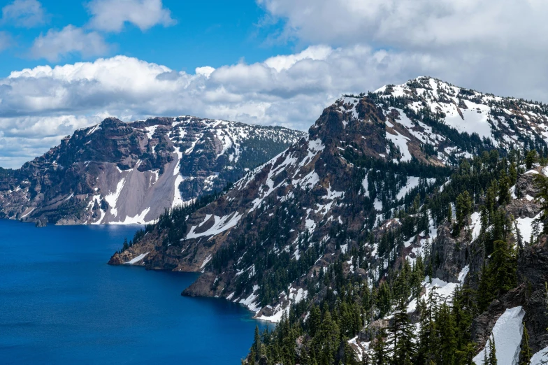 an aerial view of the mountains, a lake, and some trees