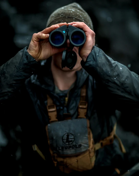 a man with backpack on holding up a pair of binoculars