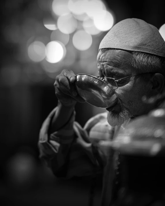 a person in glasses drinking from a silver mug