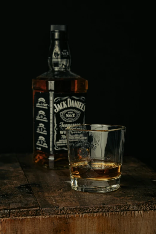 a bottle of jack daniels whisky next to a glass of bourbon