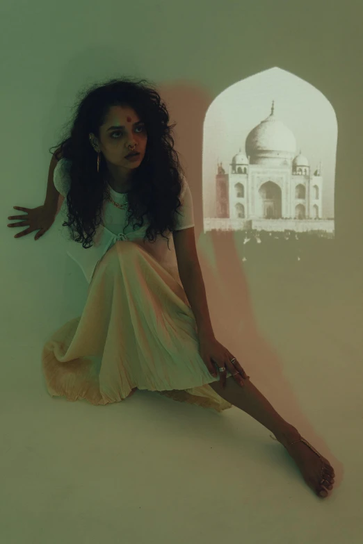 a woman sitting on the floor looking at an arch