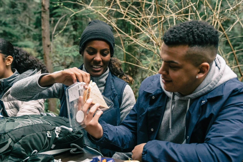 three adults sitting at a picnic table with backpacks