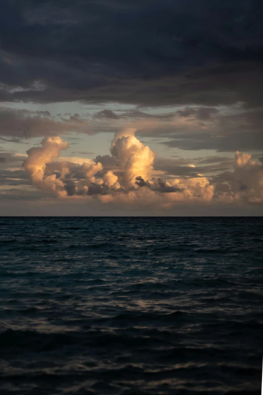 the clouds are above the ocean in a dark sky