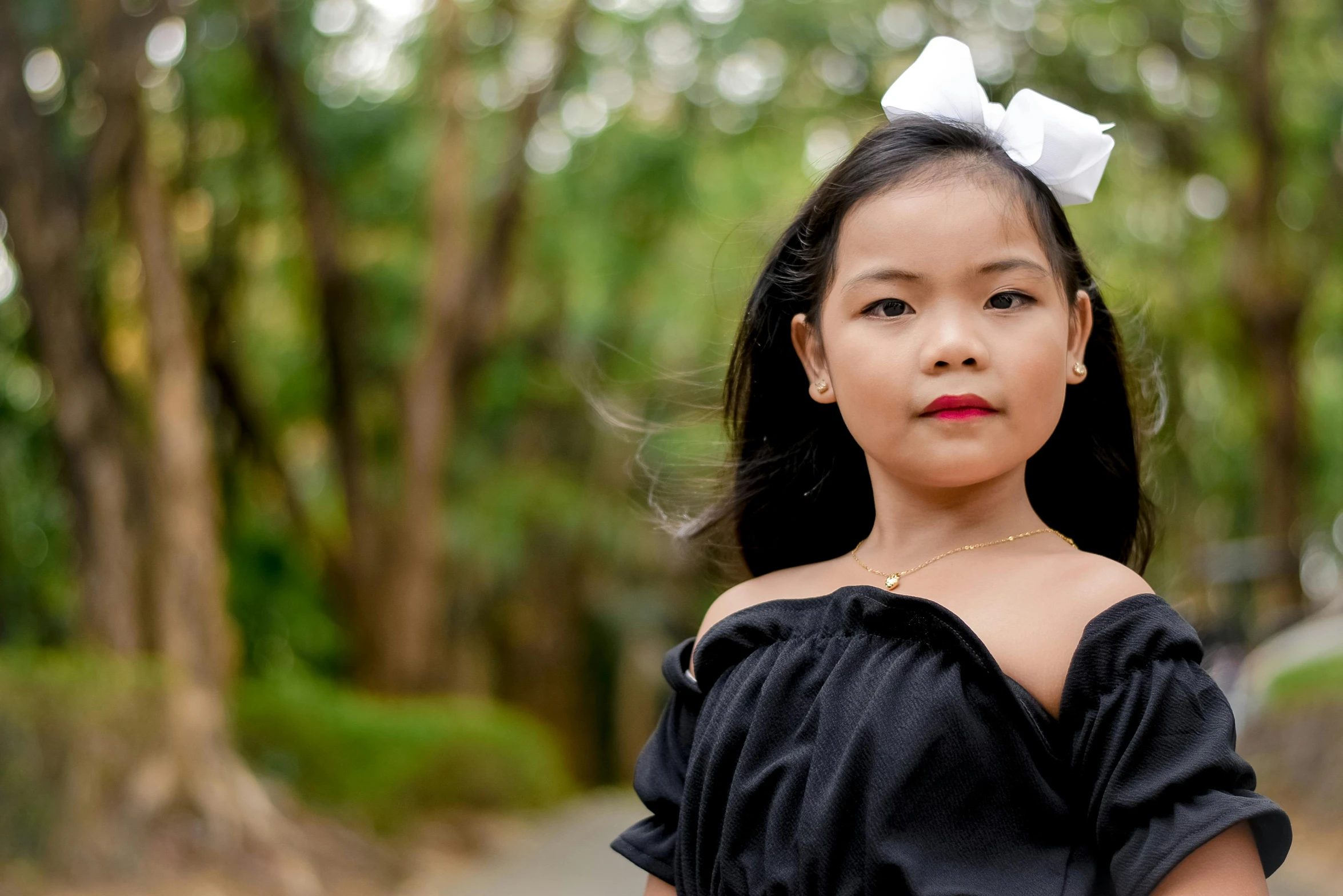 the  is wearing black dress and a big bow in her hair