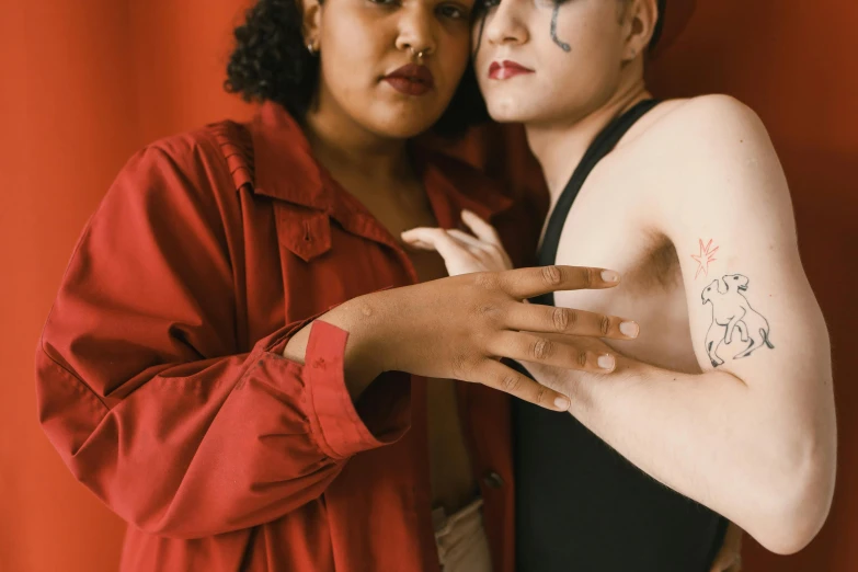 two girls pose in front of a red curtain