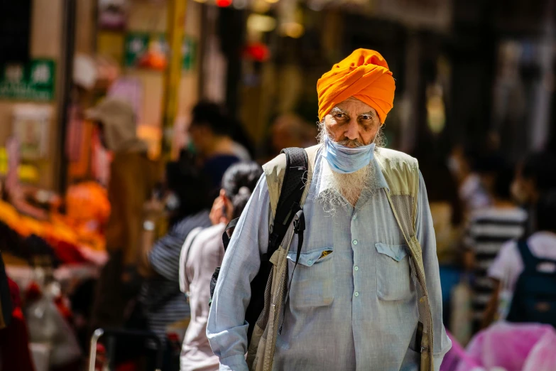 an old man wearing a turban on a busy street