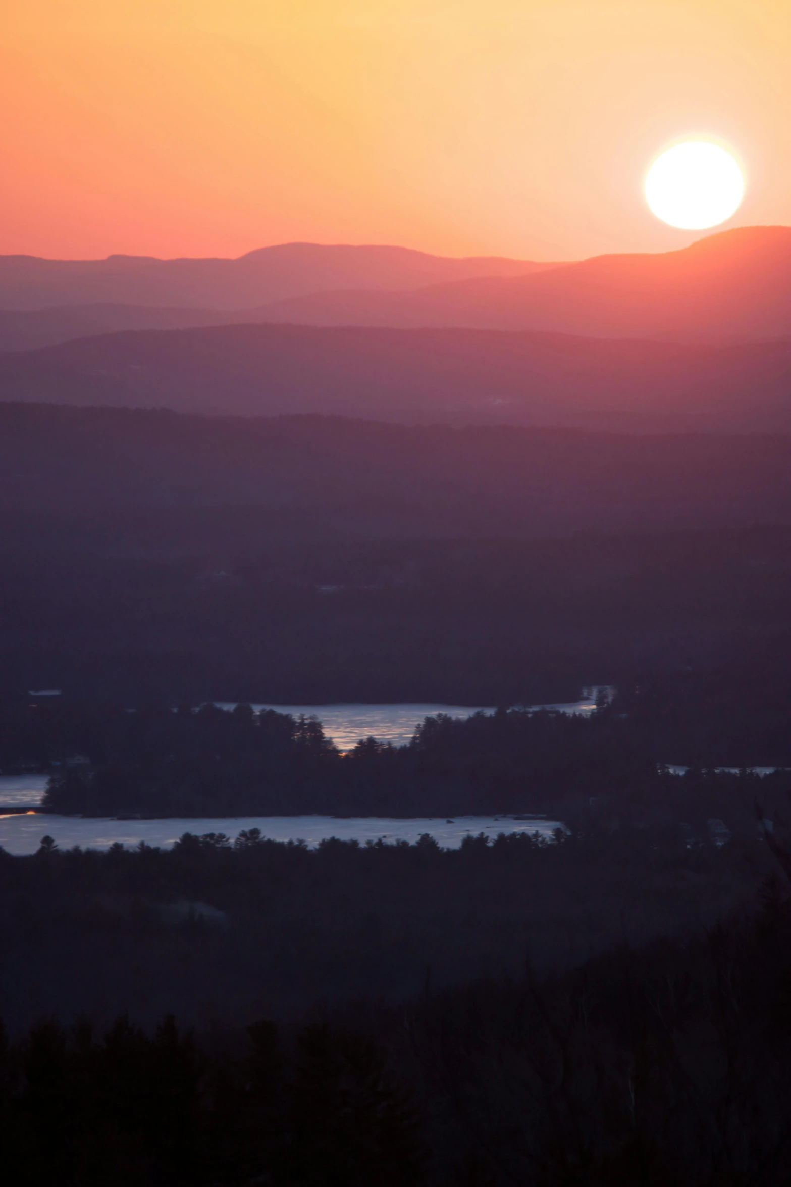 a sunrise with mountains and water in the distance