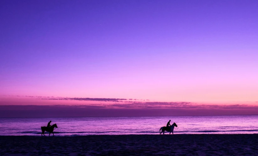 two people are riding horses along the beach