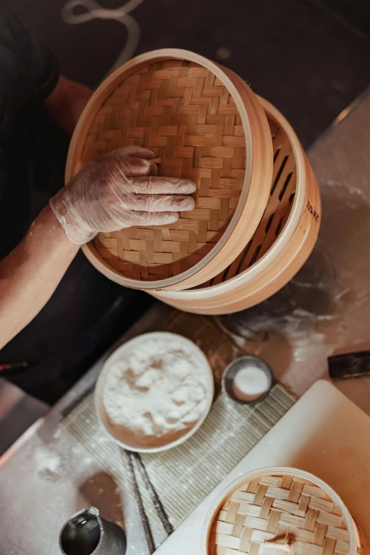 a person holding a wooden basket above some bowls