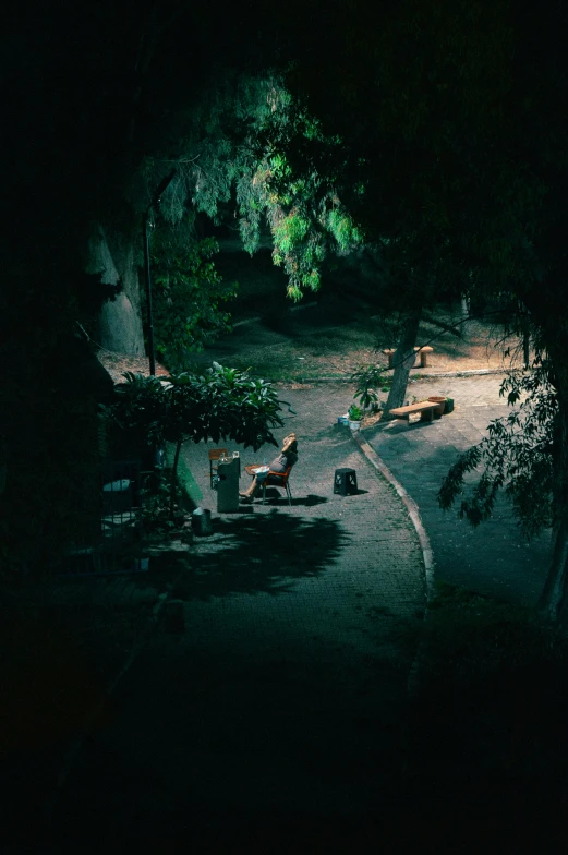 two park benches sit on the side of a small path at night