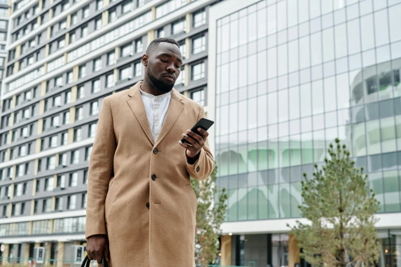 man in coat checking his cell phone outdoors