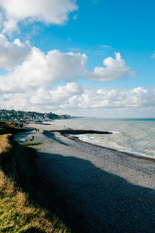 a group of people walk along the shore of an empty beach