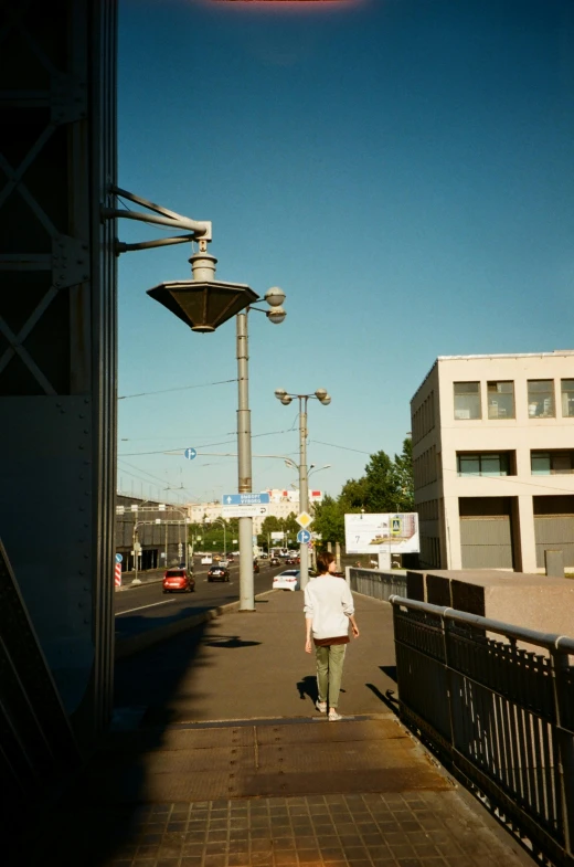 a man walking along a bridge with a red sign above him