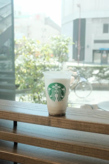 a starbucks drink is sitting on the wooden bench