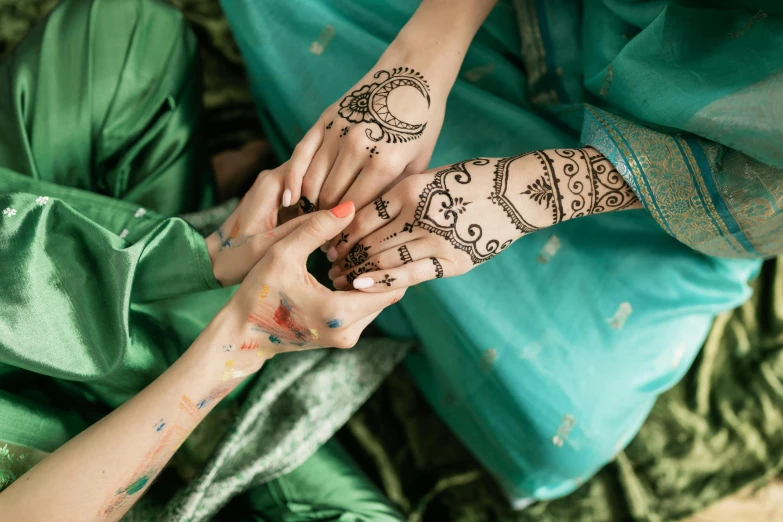 two woman hold hands with different designs on their hands