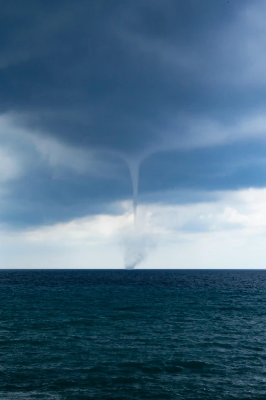 a boat is out on the ocean, just leaving a trail of smoke