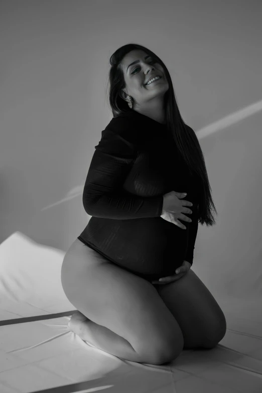 a pregnant woman poses for a black and white portrait