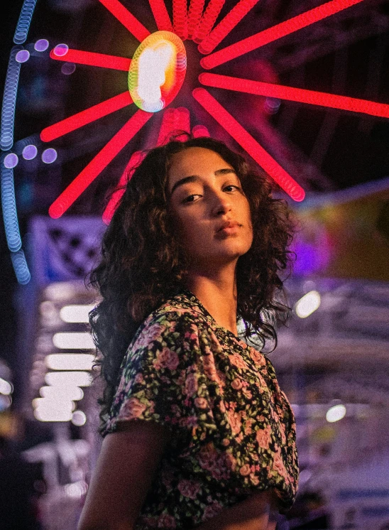 woman in front of a large colorful wheel at night