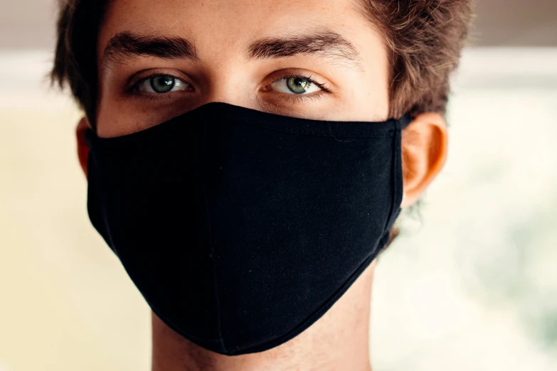 young man looking in camera, wearing a black face mask