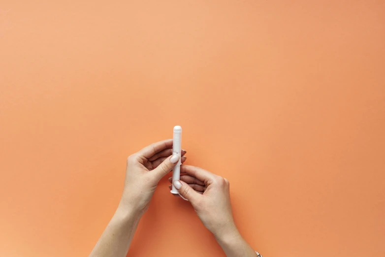 two hands are holding up soing against an orange background