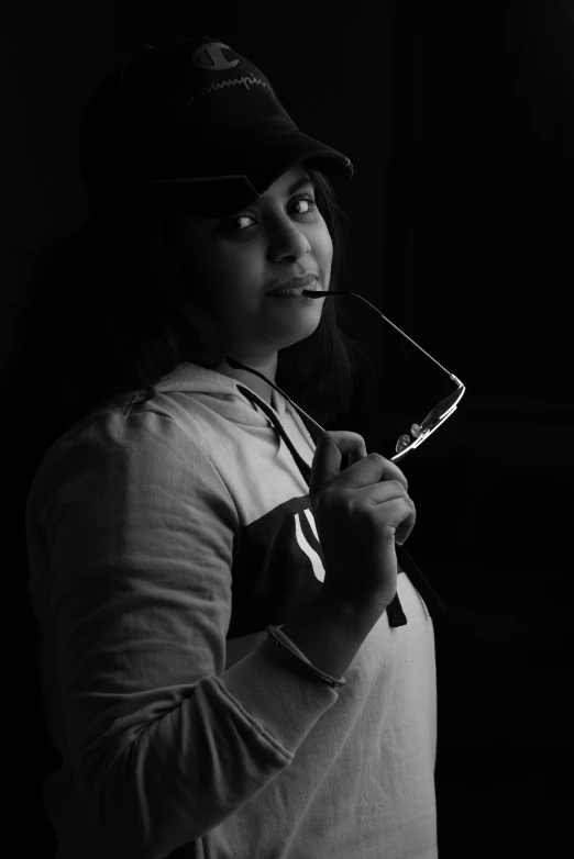 woman with baseball cap and glasses holding a racquet