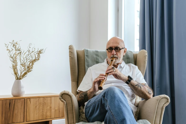 the man is playing his instrument while sitting in his living room