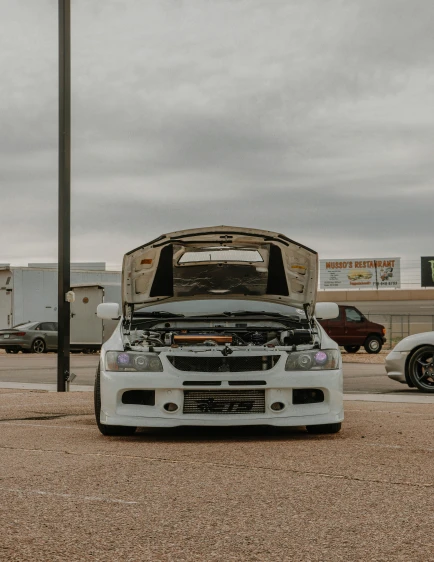 the front end of a white car in an arid lot