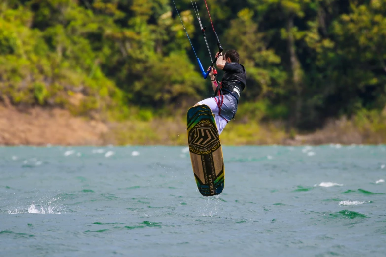 man para - sailing on open water near wooded area