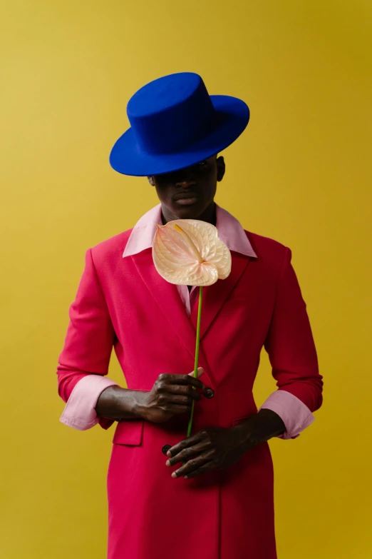 a man wearing red and a blue hat with a rose in his lap