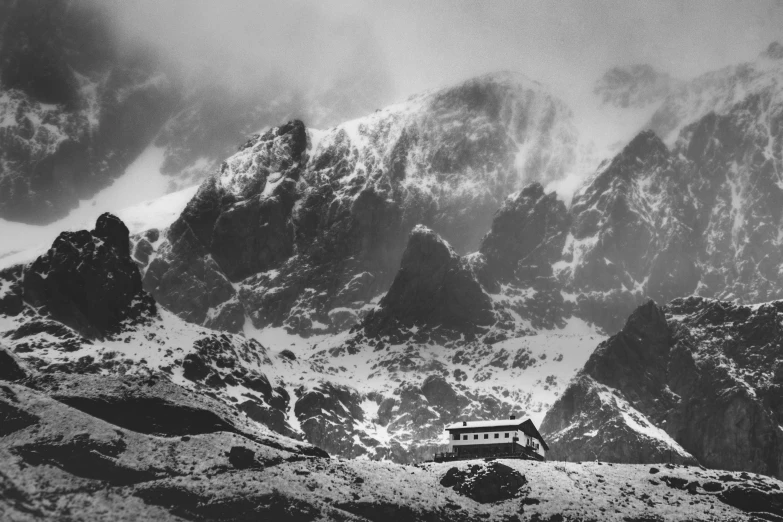 mountain range covered in snow with a building with a roof