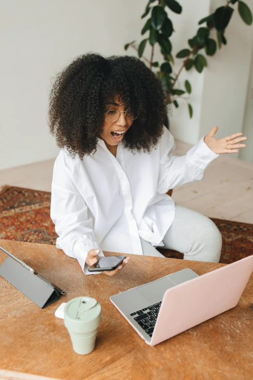 a woman sits on the ground in front of her computer and smiles