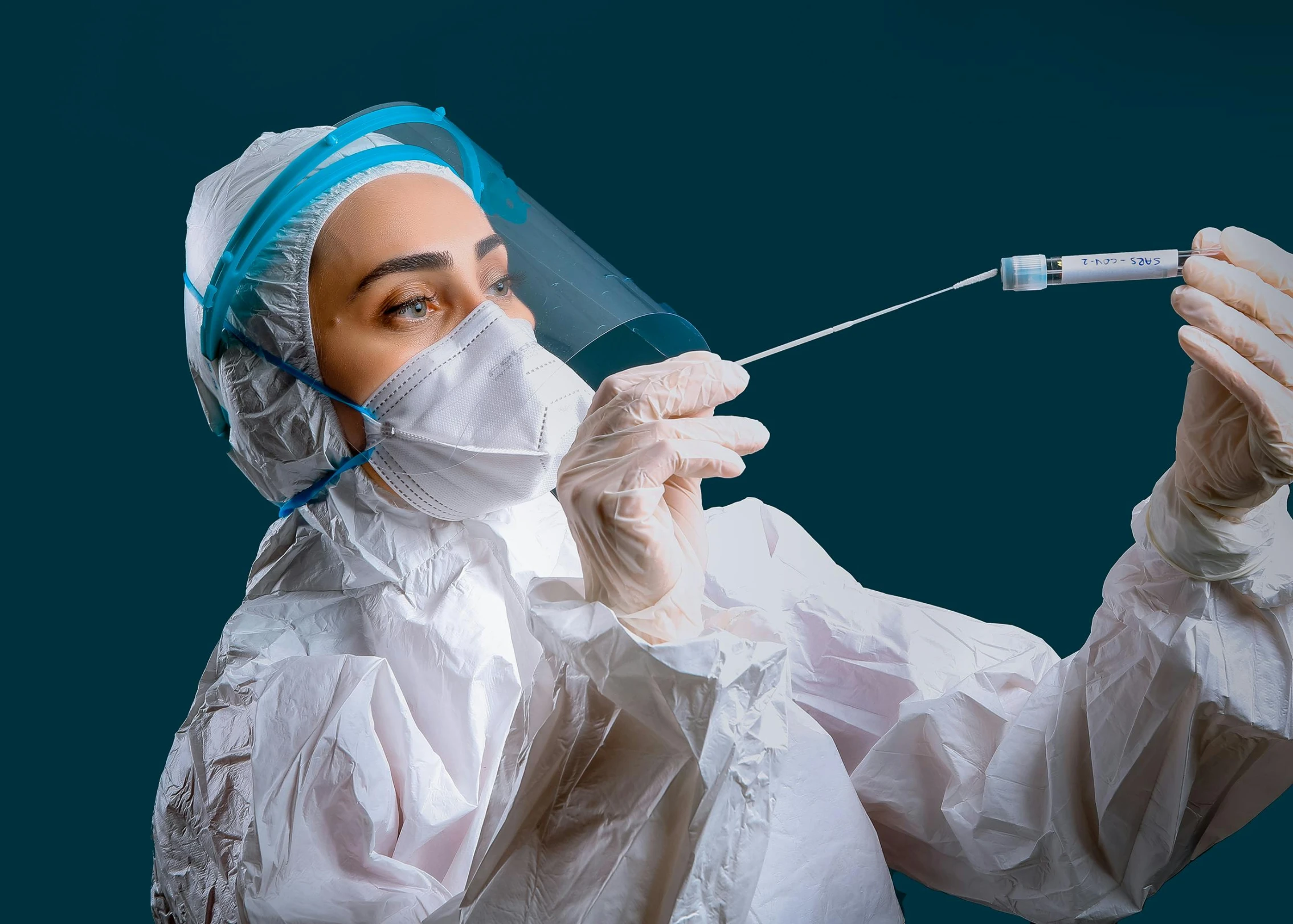 a female in a disposable medical mask and sterile gauze holding an iv tube