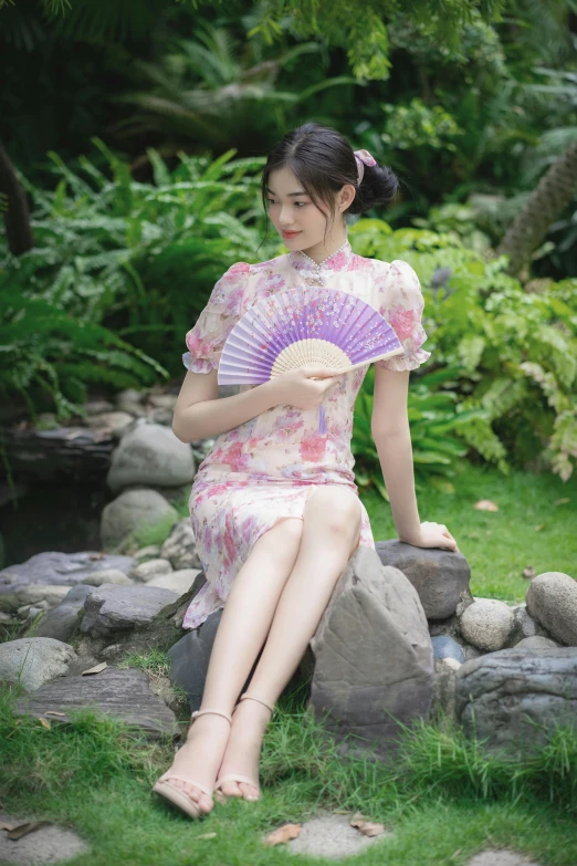 an oriental woman with short legs sitting on rocks and holding a fan